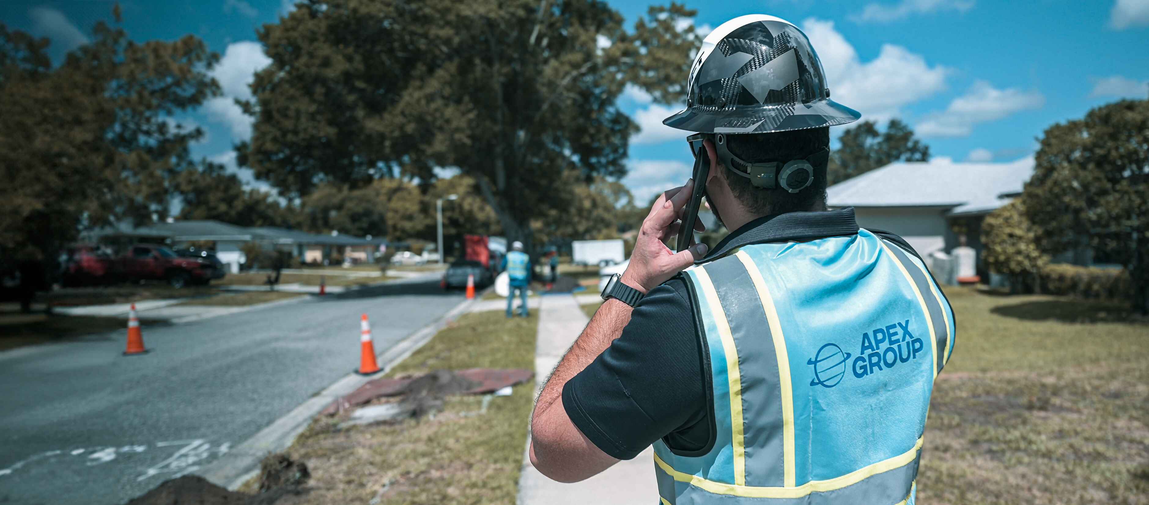 Apex crew member coordinating roadside work beside traffic cones